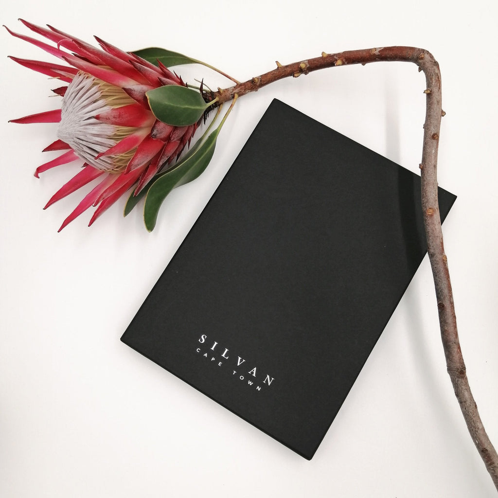 A black scarf box with silver foiled embossed branding.
